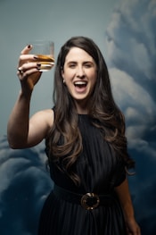 a woman in a black dress holding a glass of wine