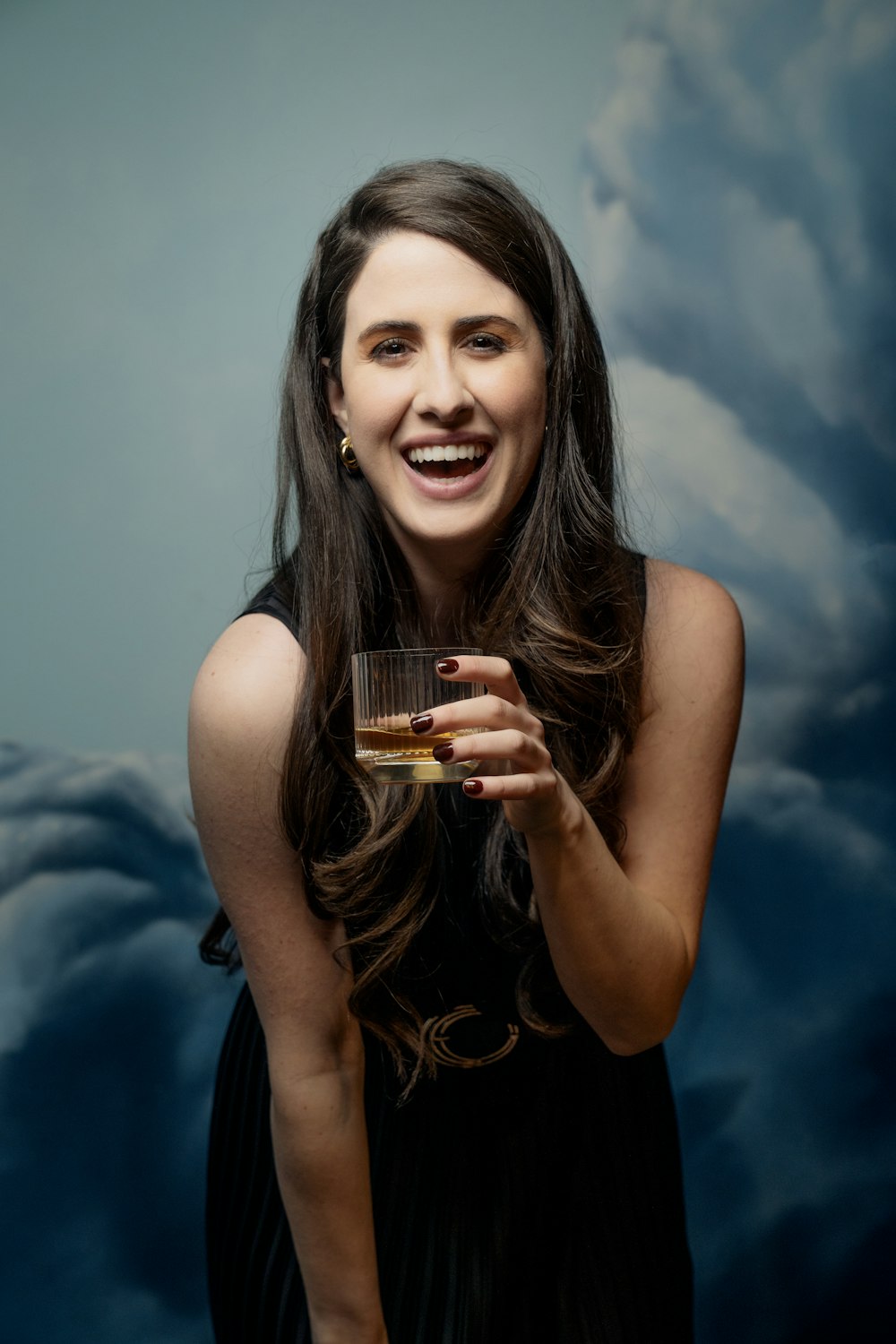 a woman in a black dress holding a glass