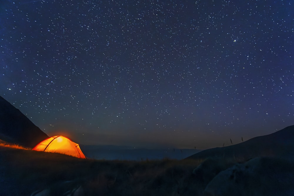 a tent pitched up on a hill under a night sky with stars