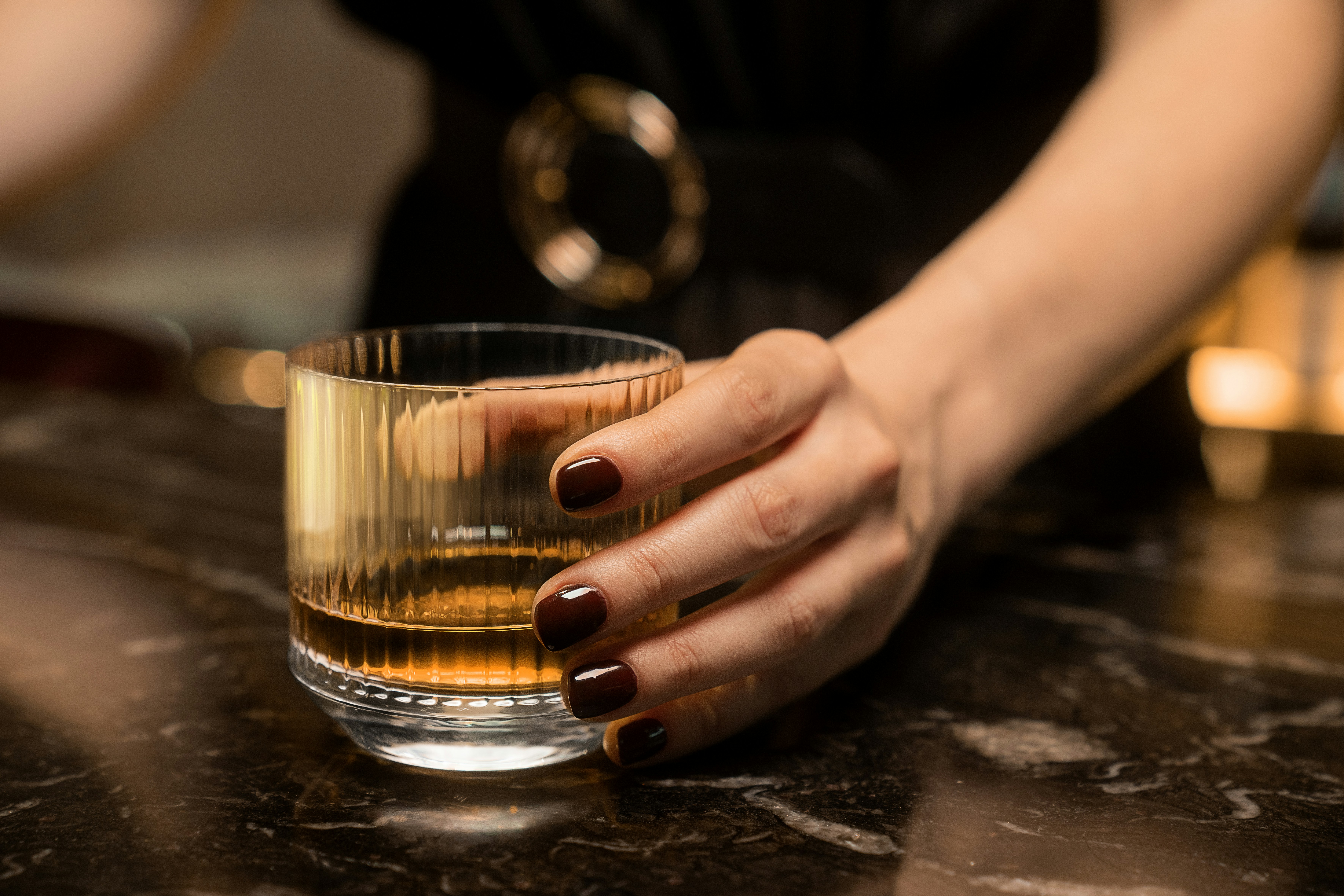 a woman holding a glass of alcohol on a table