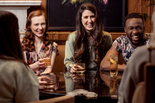 A lively group of friends laughing together at a quirky Portland pub during a themed crawl.