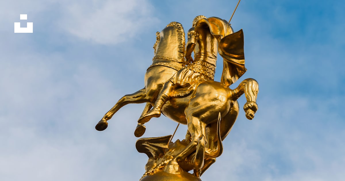 A statue of a man riding a horse on top of a pillar photo – Free ...