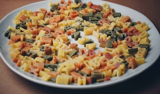 Brightly colored pasta shapes and craft supplies spread out on a table, ready for creative use.