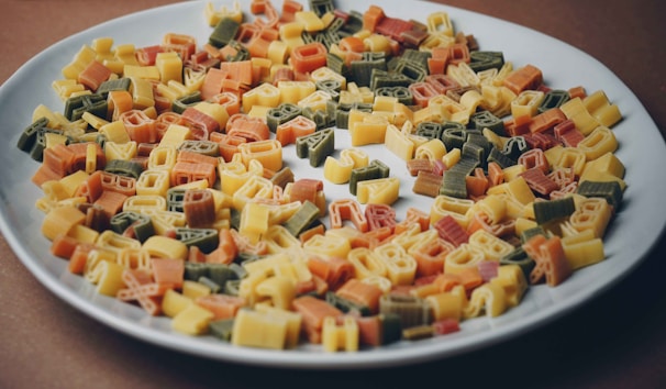 Brightly colored pasta shapes and craft supplies spread out on a table, ready for creative use.