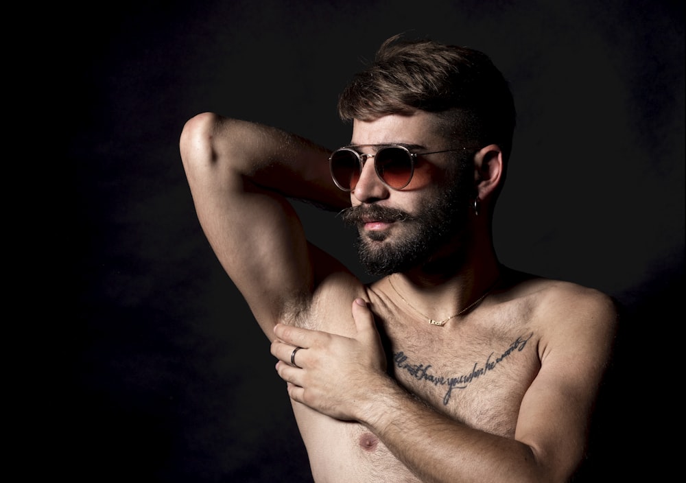 a shirtless man with a beard and sunglasses