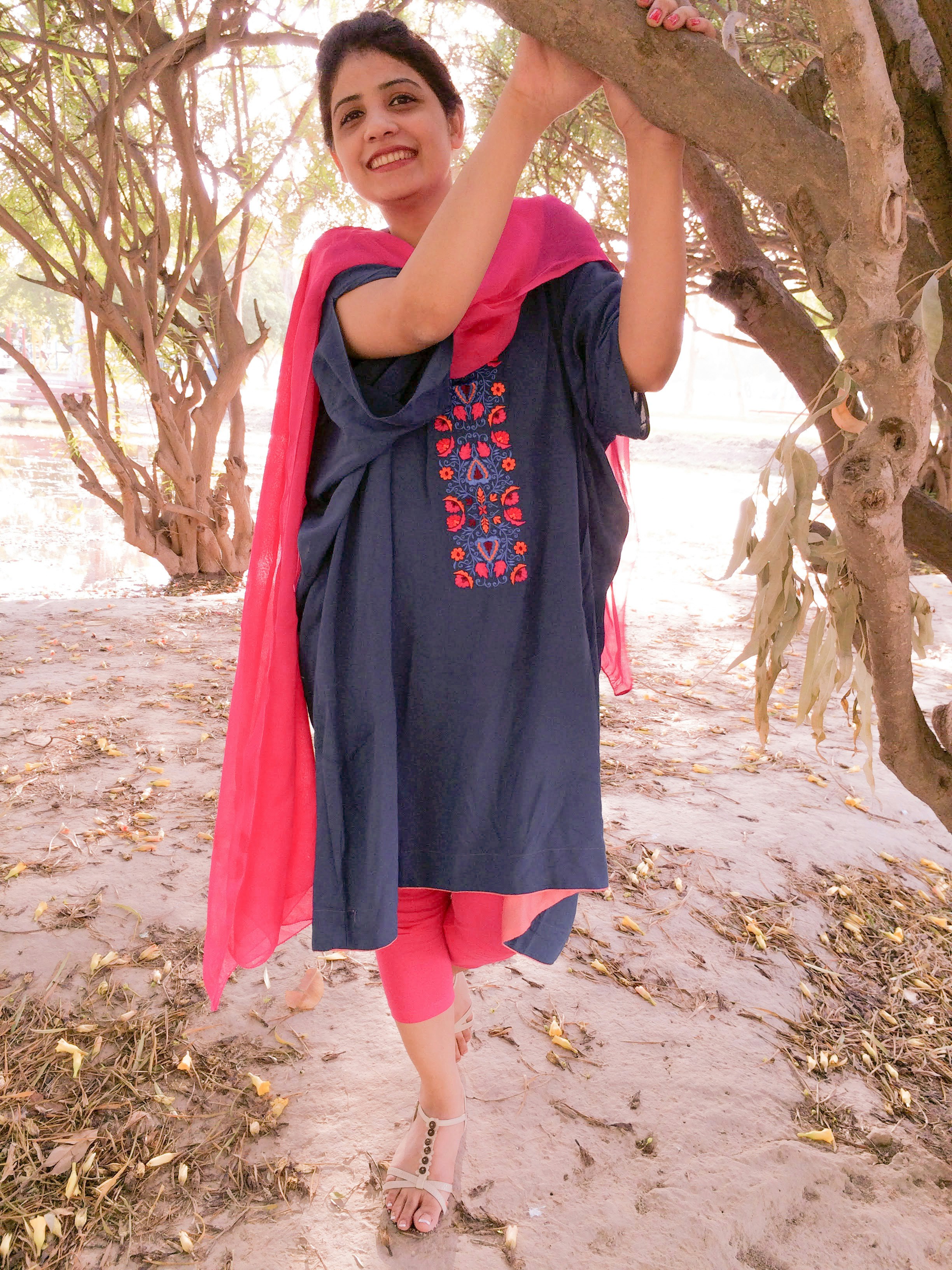 Wanita muda dengan tunik biru dan legging merah muda tersenyum.