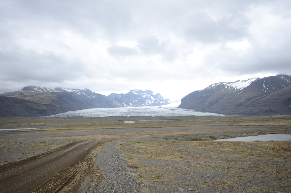 a dirt road with a glacier in the background