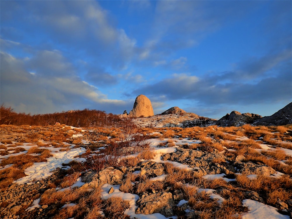 a rocky outcropping covered in snow under a cloudy sky
