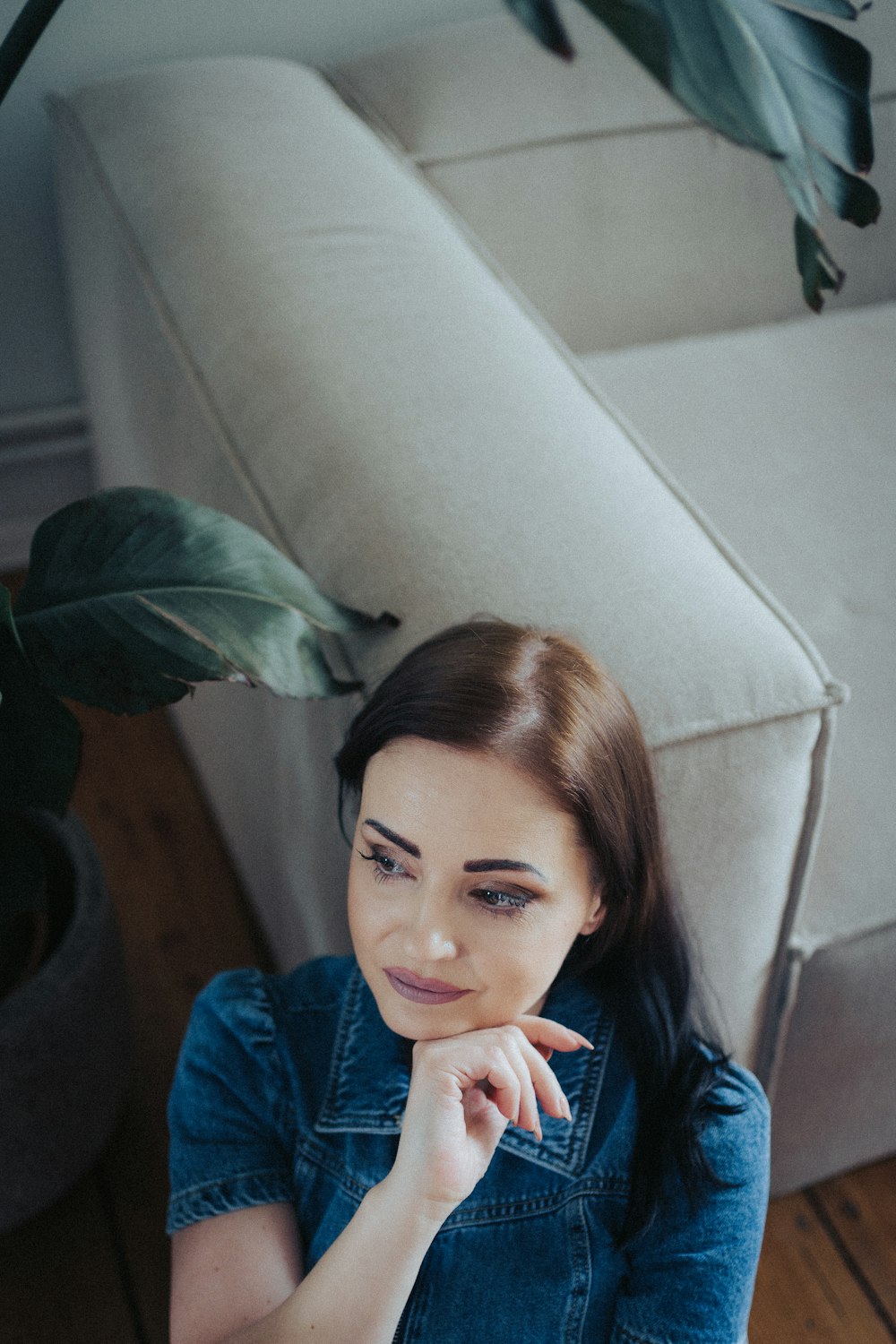 a woman sitting on a couch with her hand on her chin