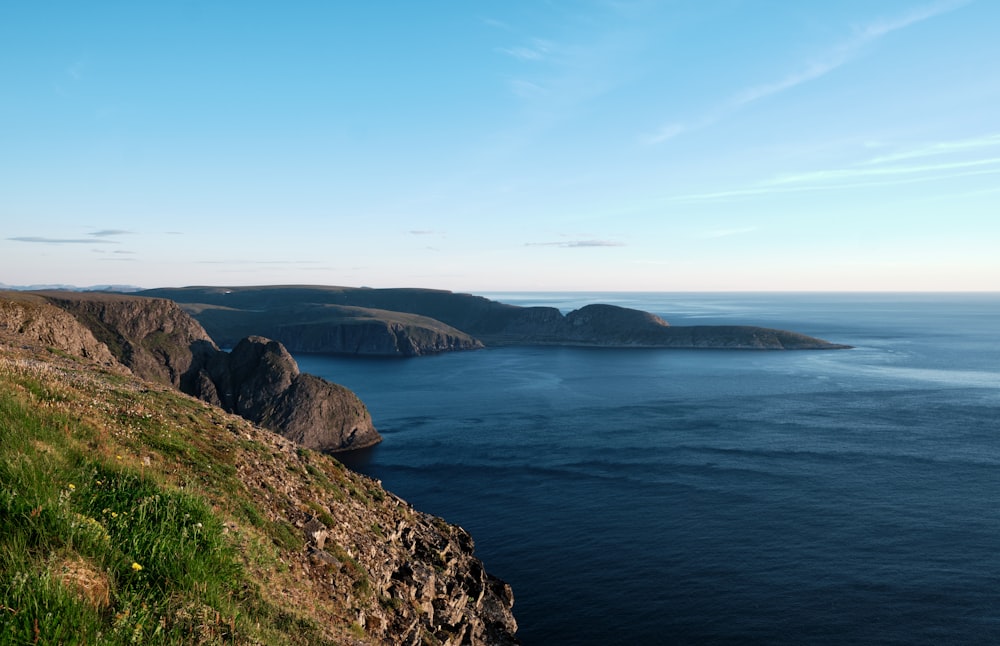 a grassy hill with a body of water in the background