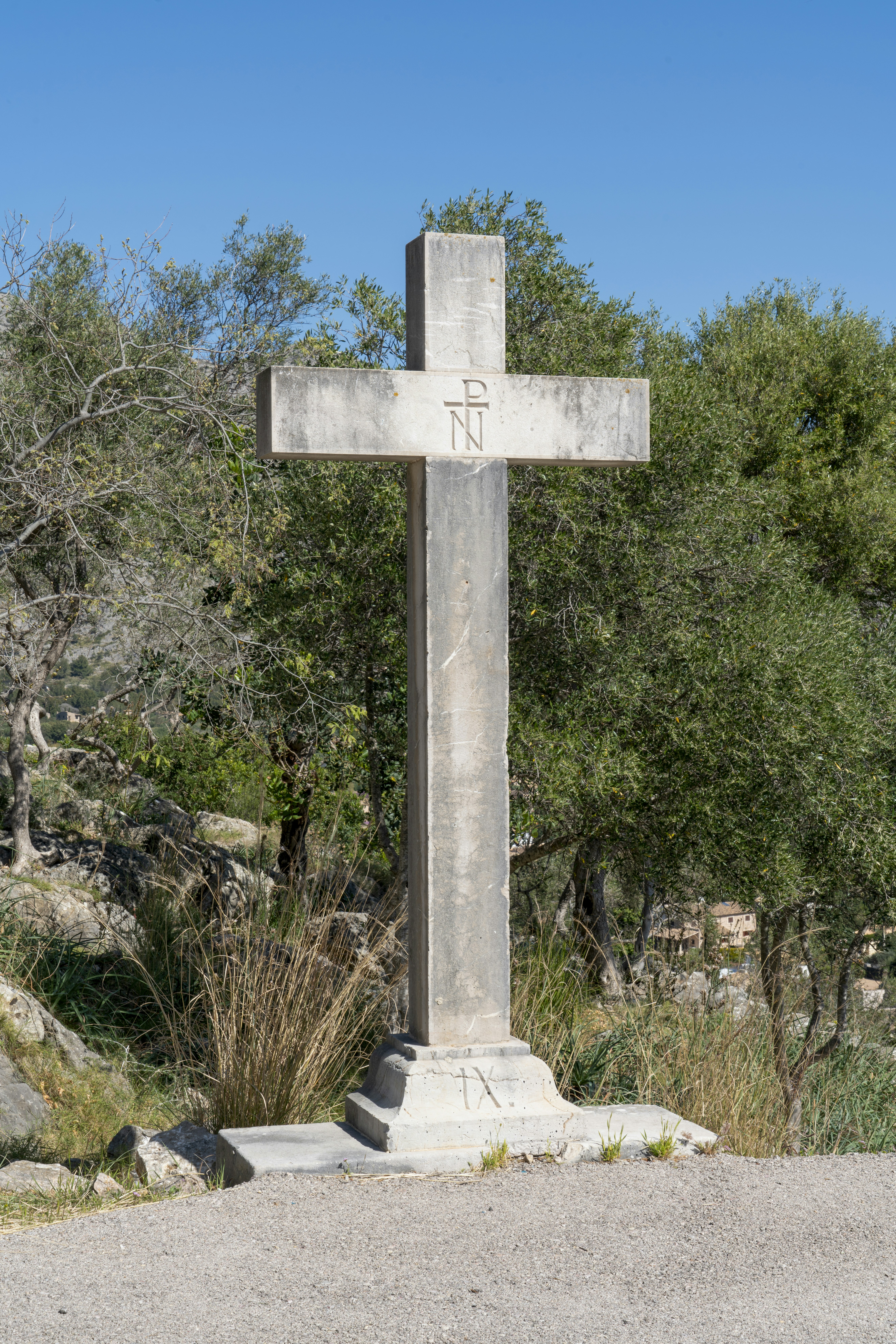 a large stone cross sitting in the middle of a forest