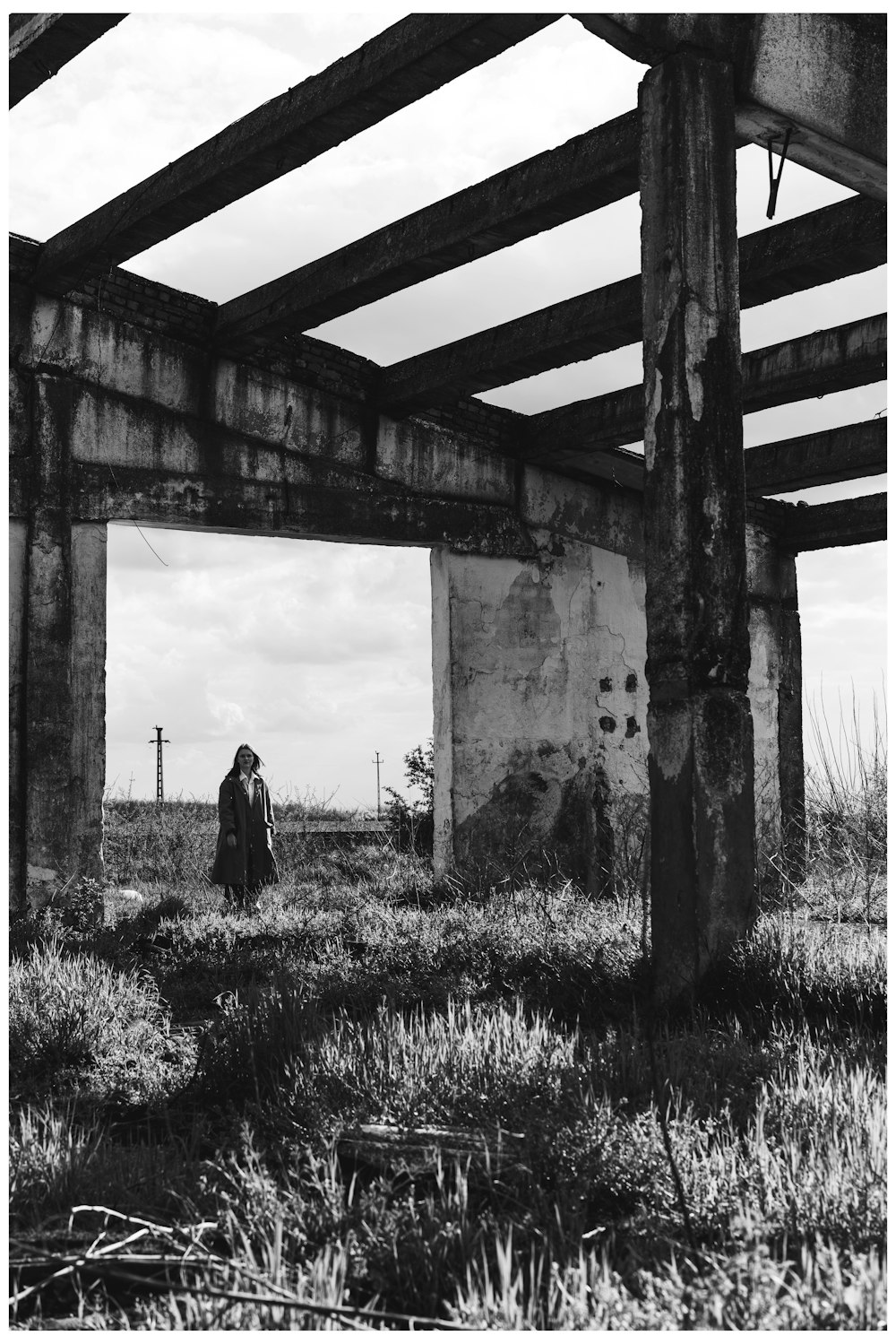 a black and white photo of a person standing under a bridge