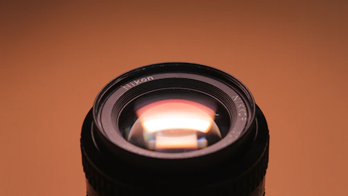 Close-up of a camera lens reflecting warm gold light, symbolizing premium cinematic production.