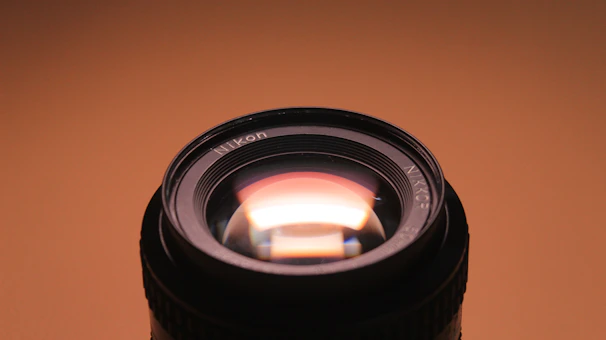 Artistic shot of premium lenses reflecting soft orange hues on a white backdrop.