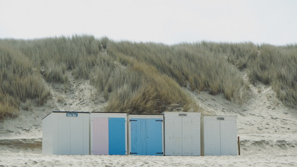 Una hilera de cabañas de playa sentadas en la parte superior de una playa de arena