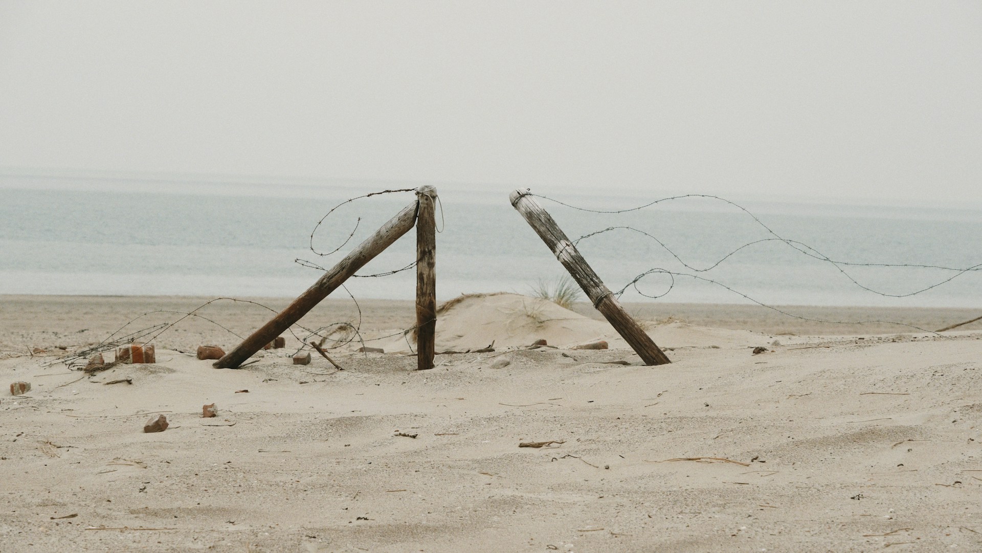 a couple of wooden posts sitting on top of a sandy beach