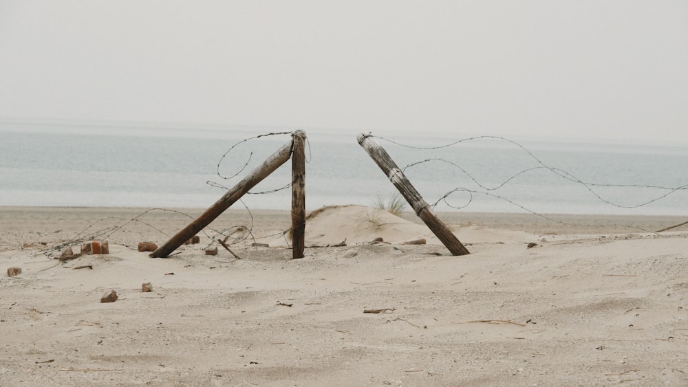 a couple of wooden posts sitting on top of a sandy beach