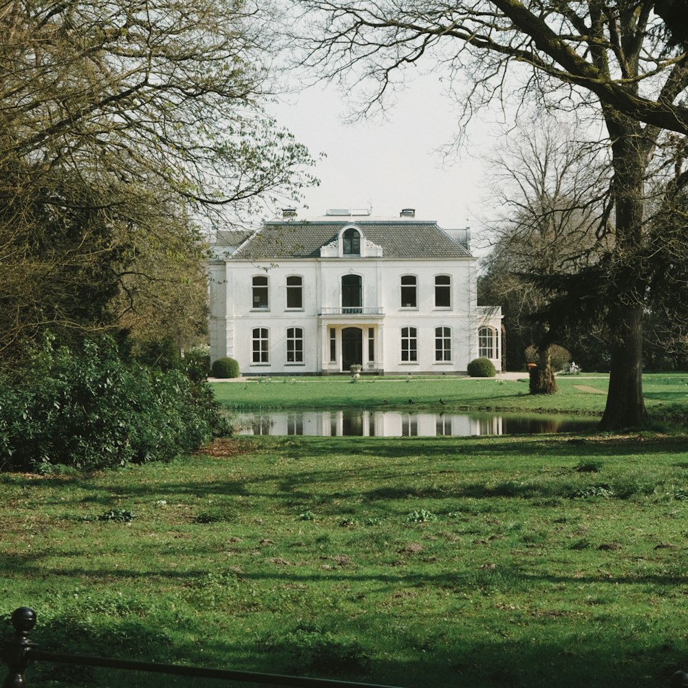 a large white house sitting in the middle of a lush green field