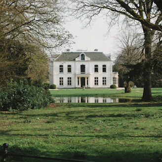 a large white house sitting in the middle of a lush green field