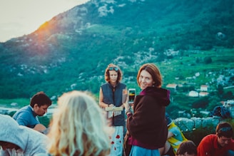 A vibrant group photo of children, youth, and adults singing together outdoors in a mountain setting.