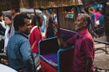 A group of e-rickshaw owners gathered together, sharing stories and laughter under the warm sunlight.
