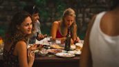 A group of diverse family members laughing and enjoying a meal outdoors.