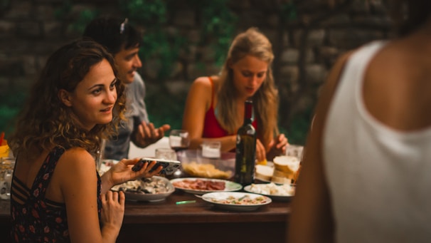 A cheerful group of friends dining outdoors near the Atlantic coast, enjoying local dishes together.