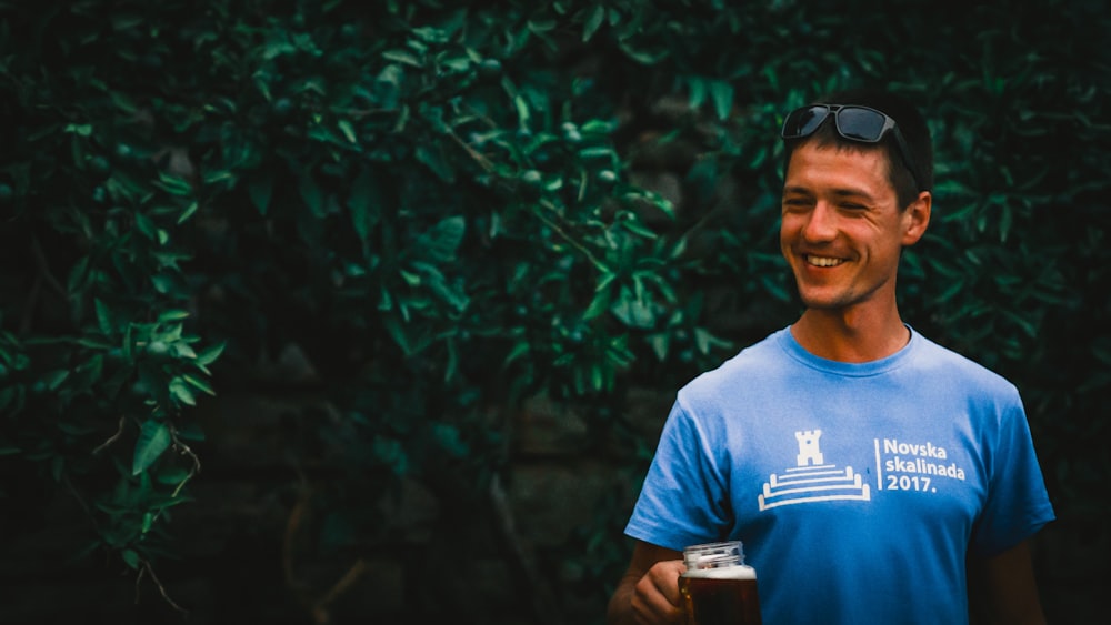a man in a blue shirt holding a glass of beer