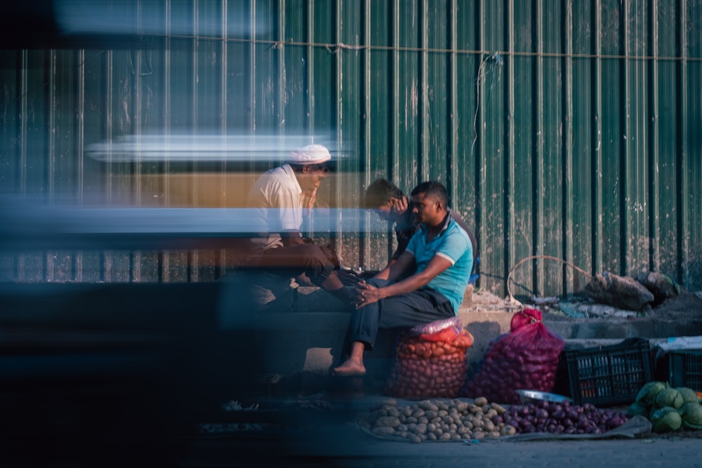a man sitting on a bench next to a pile of produce