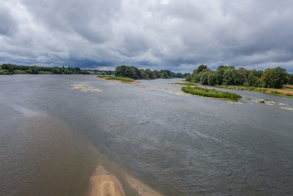 uno specchio d'acqua circondato da terra e alberi