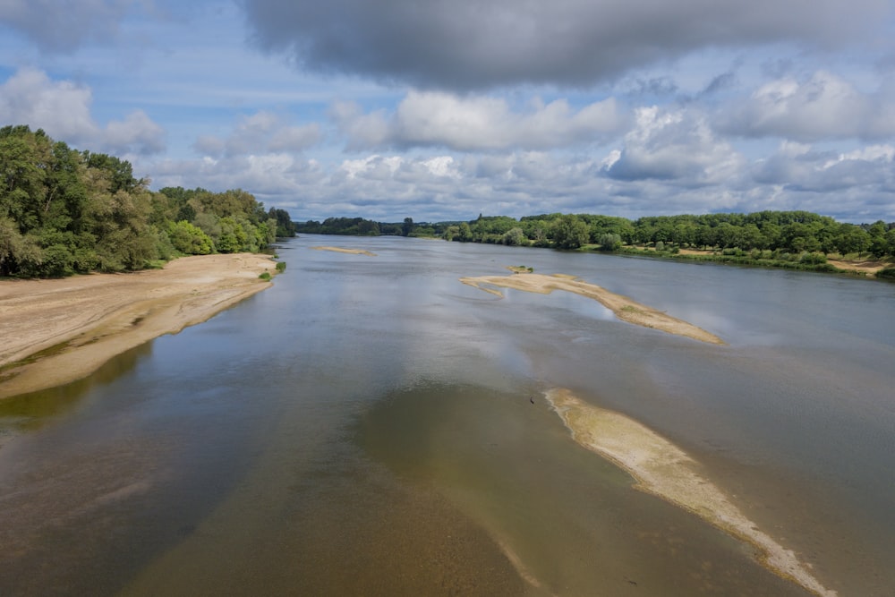 a body of water surrounded by trees under a cloudy sky