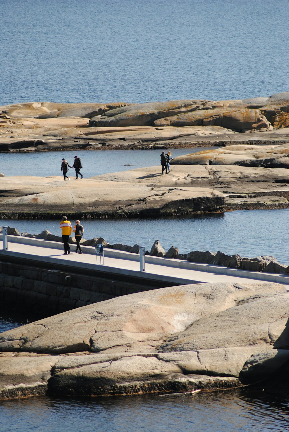 a group of people walking across a bridge over a body of water