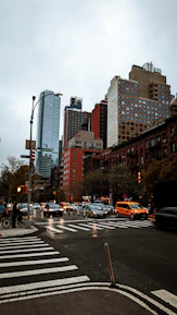 An old Manhattan street scene in the late seventies under a cloudy sky, busy with taxis and pedestrians.