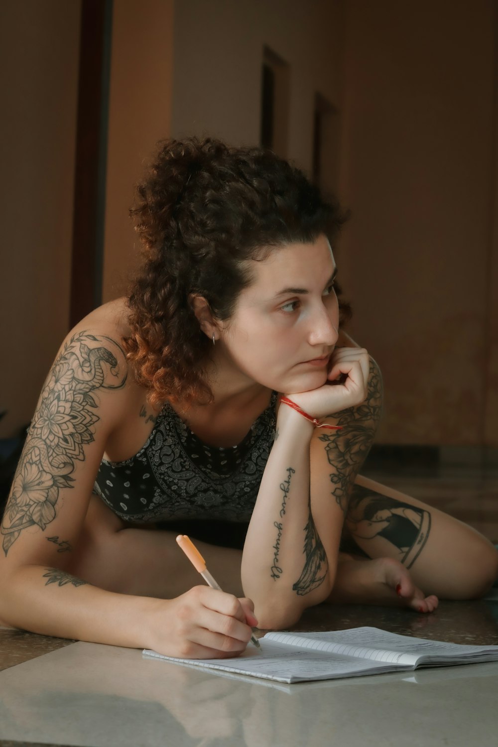 a woman sitting on the floor writing on a piece of paper