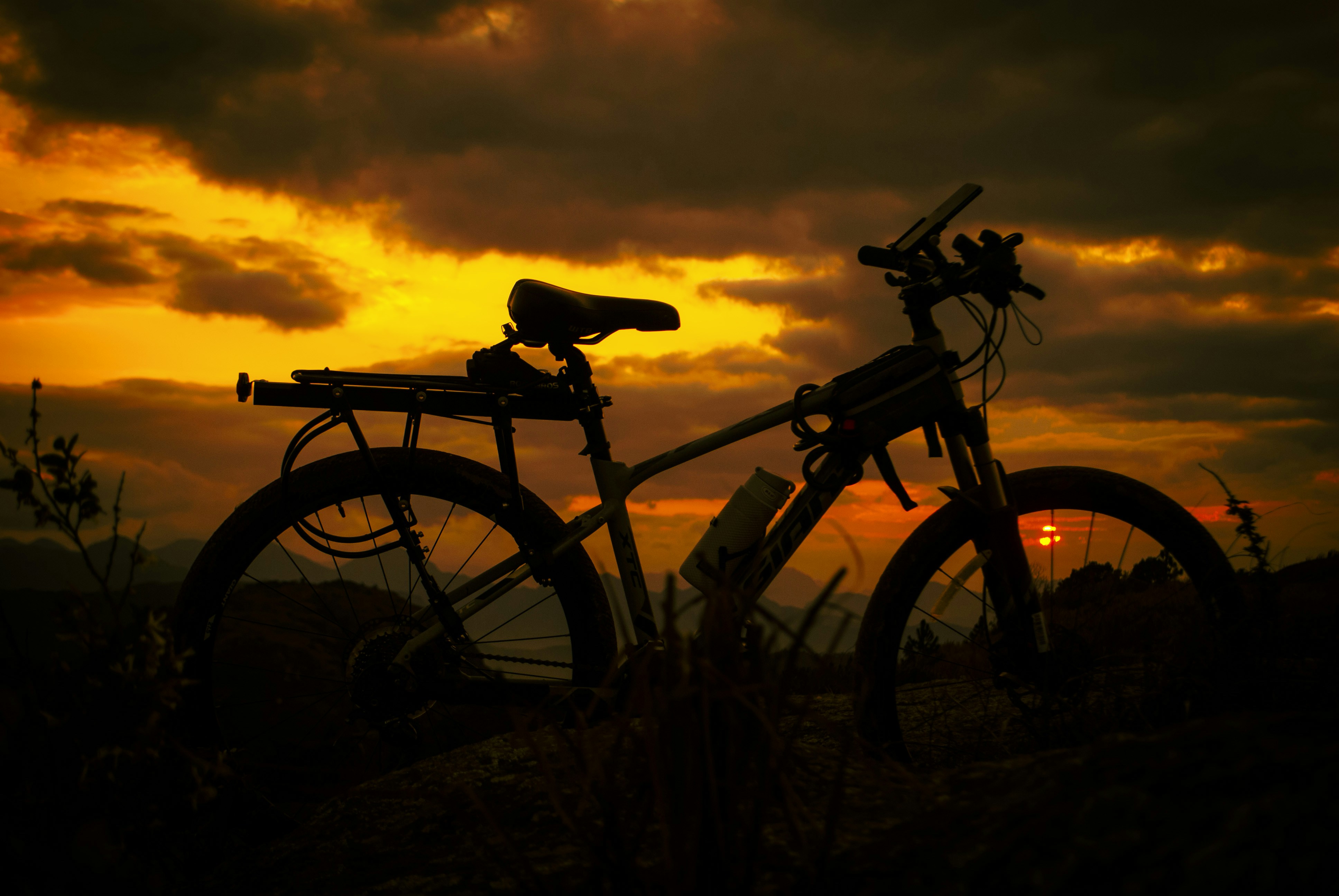 a bike is parked in the grass at sunset