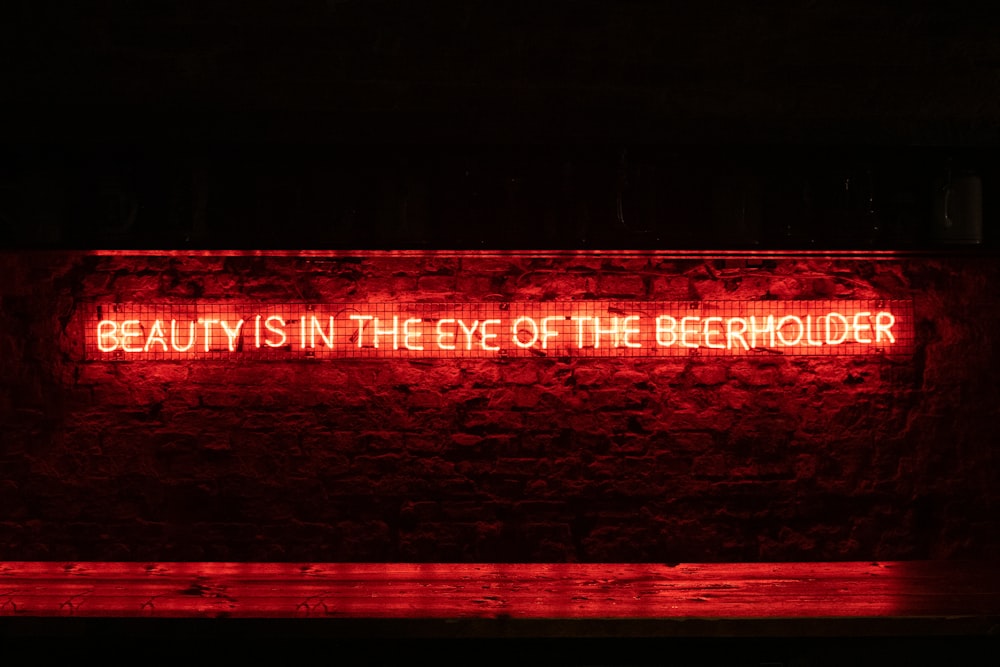 a red neon sign that reads beauty is in the eye of the behold