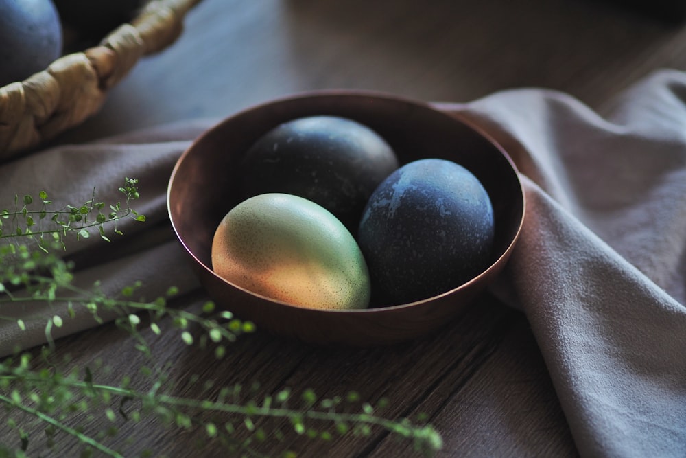 a bowl filled with three different colored eggs