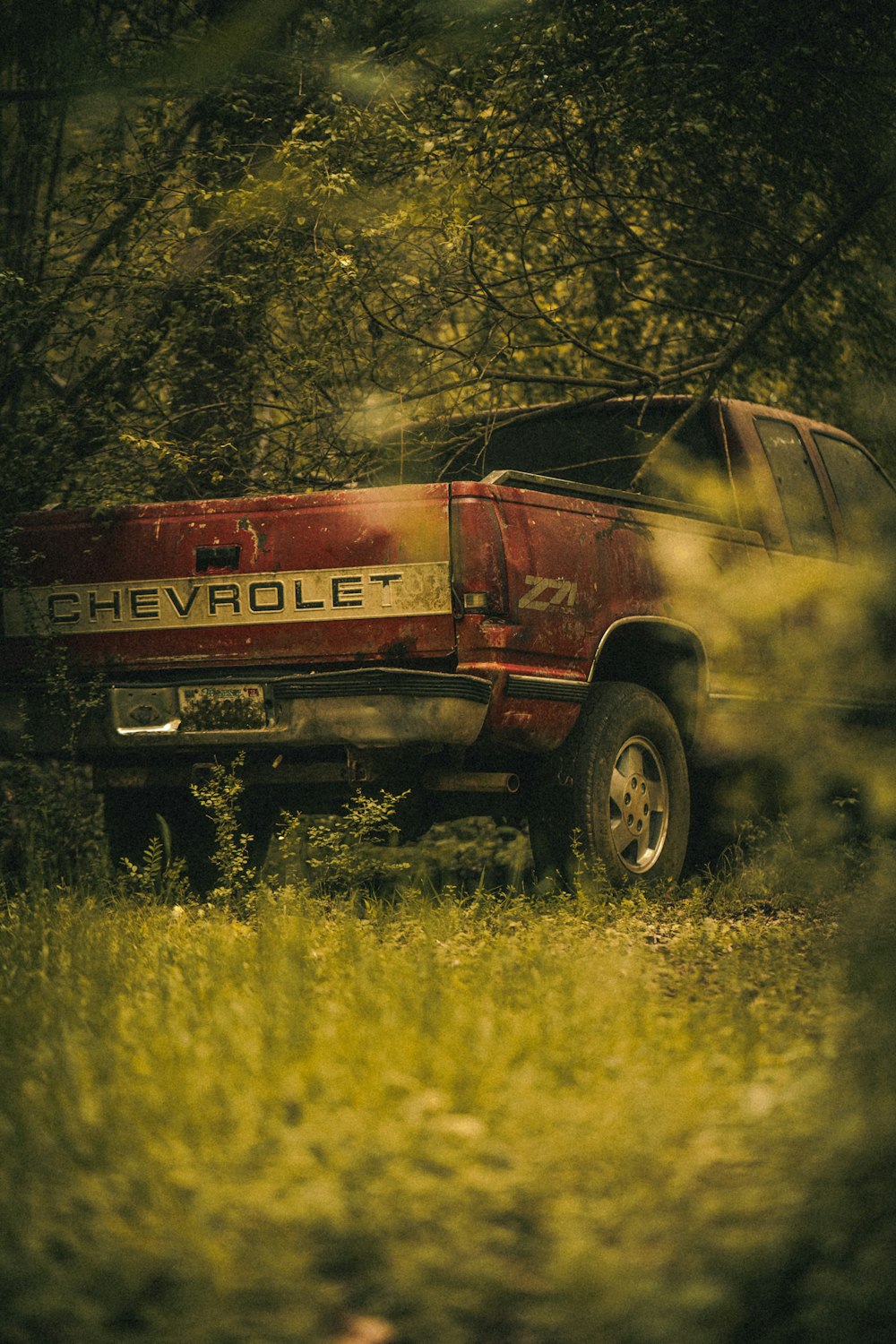 a red chevrolet truck parked in the woods