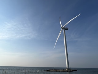 A researcher testing a small-scale ocean wave energy converter on a coastal platform during sunrise.