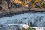 Close-up aerial view of a coastal cliff with waves crashing below.
