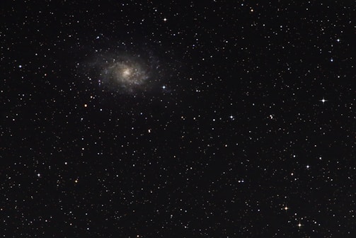 A vast galaxy swirling with stars and ethereal light, surrounded by angelic figures in worship.