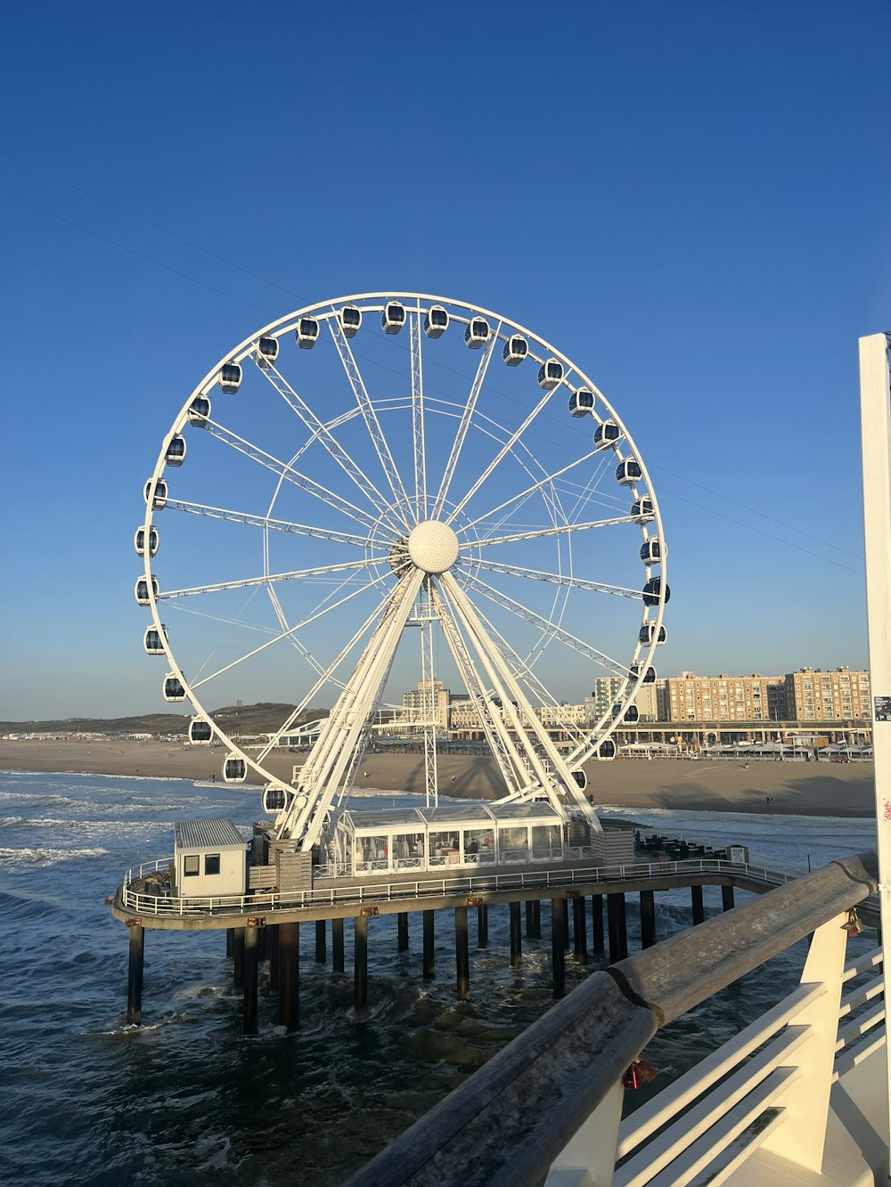 a ferris wheel sitting on top of a pier next to the ocean