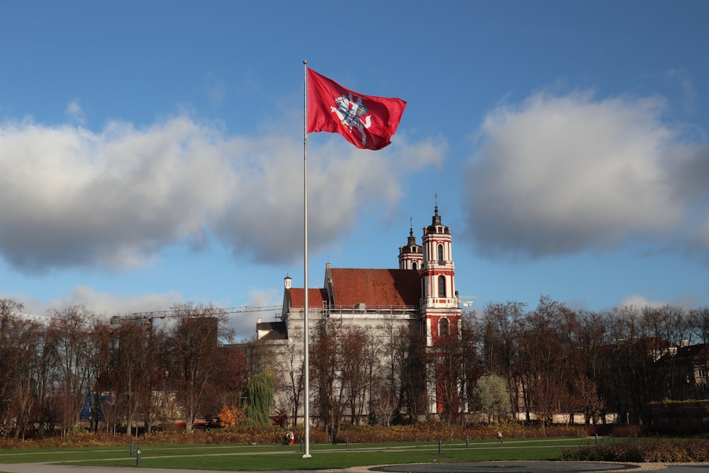a red flag flying in front of a large building