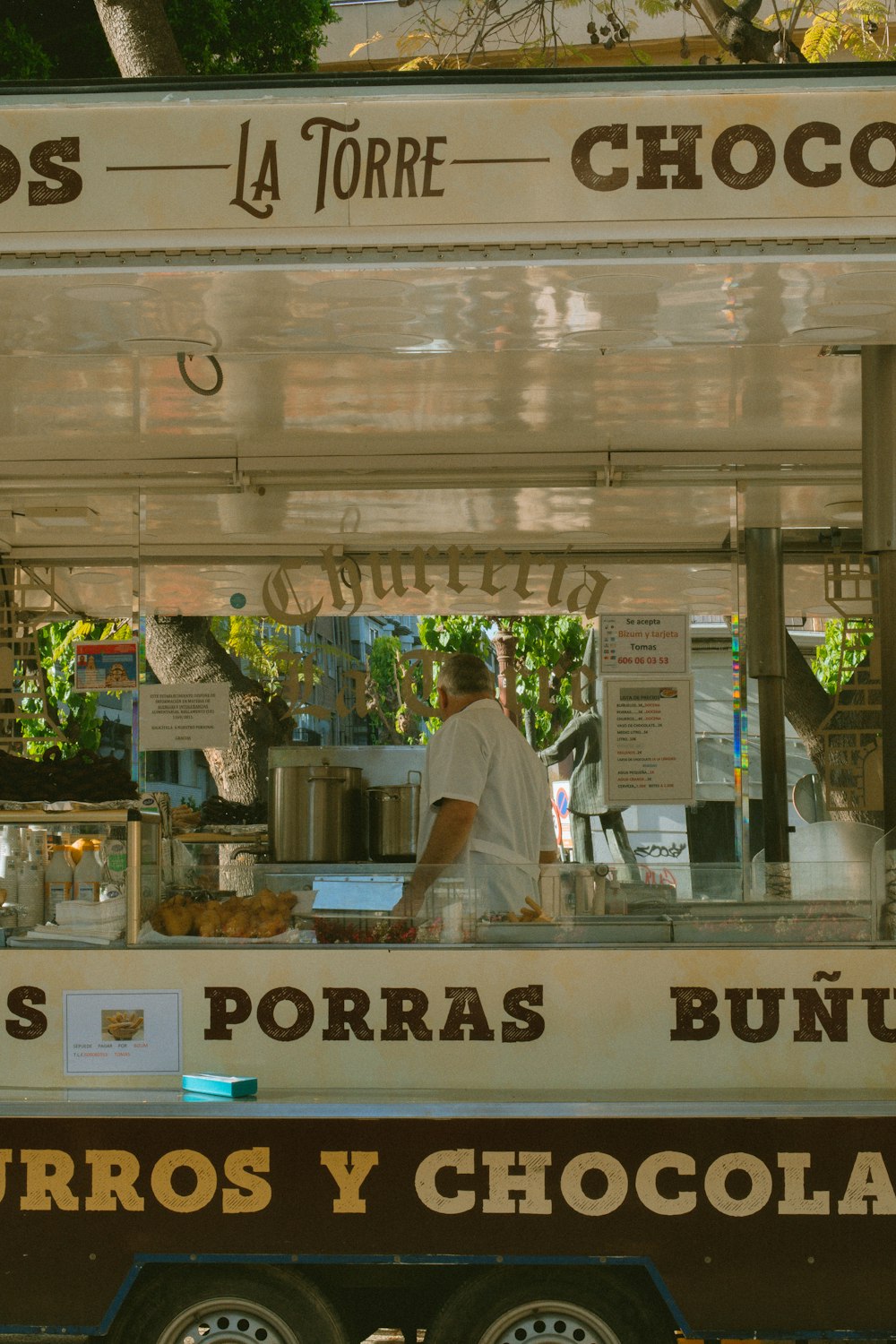 a man standing behind a food cart selling chocolate