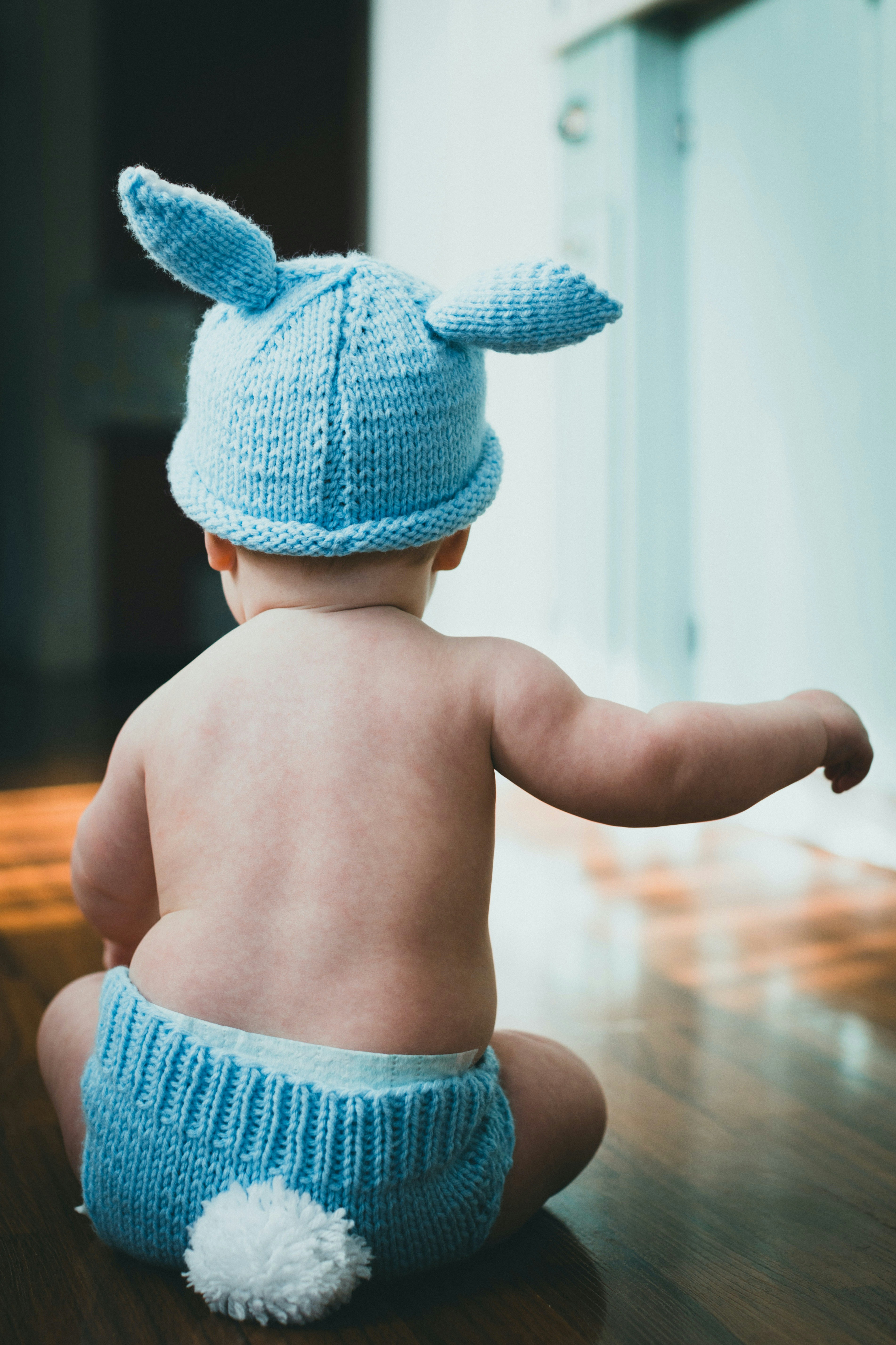 Seorang bayi mengenakan topi rajutan biru dan popok