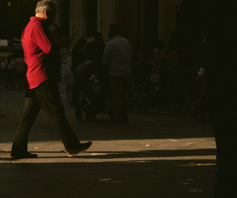 a man in a red shirt walking down a street