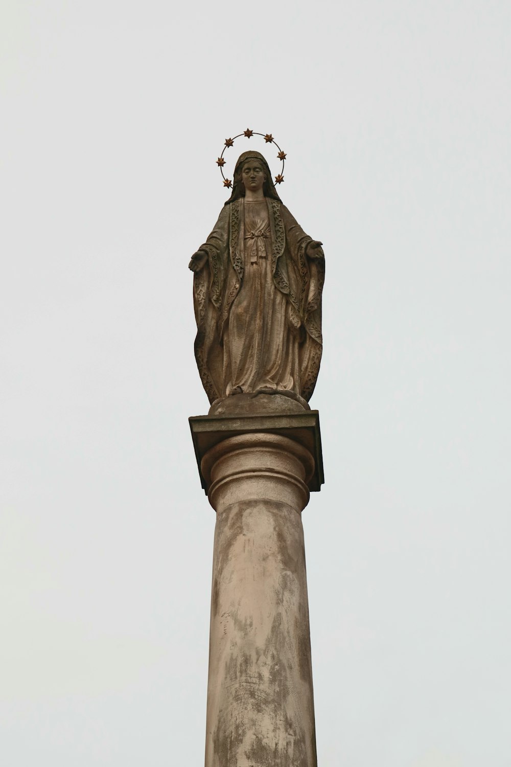 a statue of the virgin mary on top of a pillar