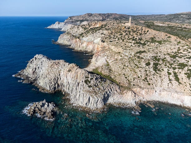 Close-up of the Faro del Caballo lighthouse perched on rugged cliffs with emerald waters below.