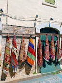 a row of colorful rugs hanging on a wall