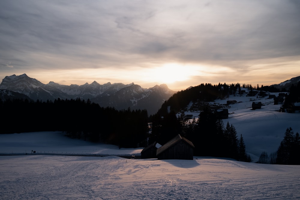 the sun is setting over a snowy mountain